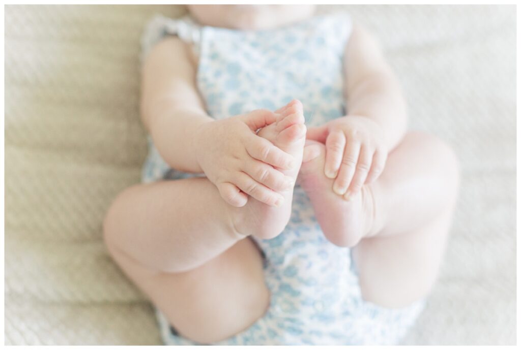 A detail photo of a baby playing with their feet.