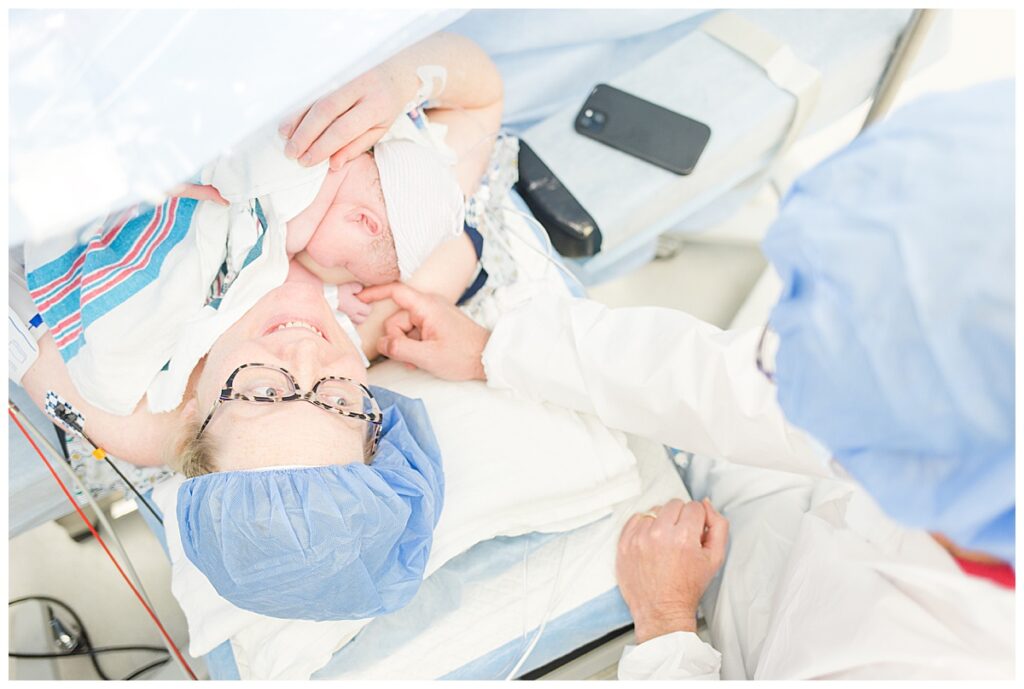 A mom lays on the operating table holding her new baby following a positive scheduled c-section.