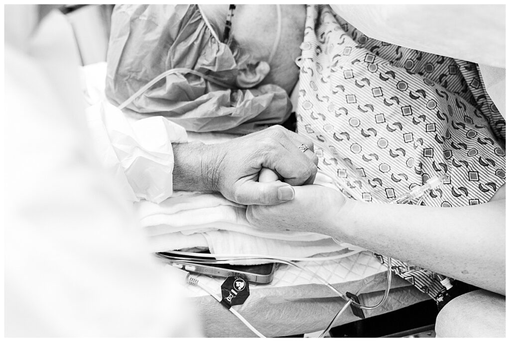 Two parents hold hands while awaiting the birth of their baby.