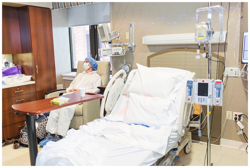 A dad sits beside an empty hospital bed waiting to be taken back into the operating room for mom's c-section.